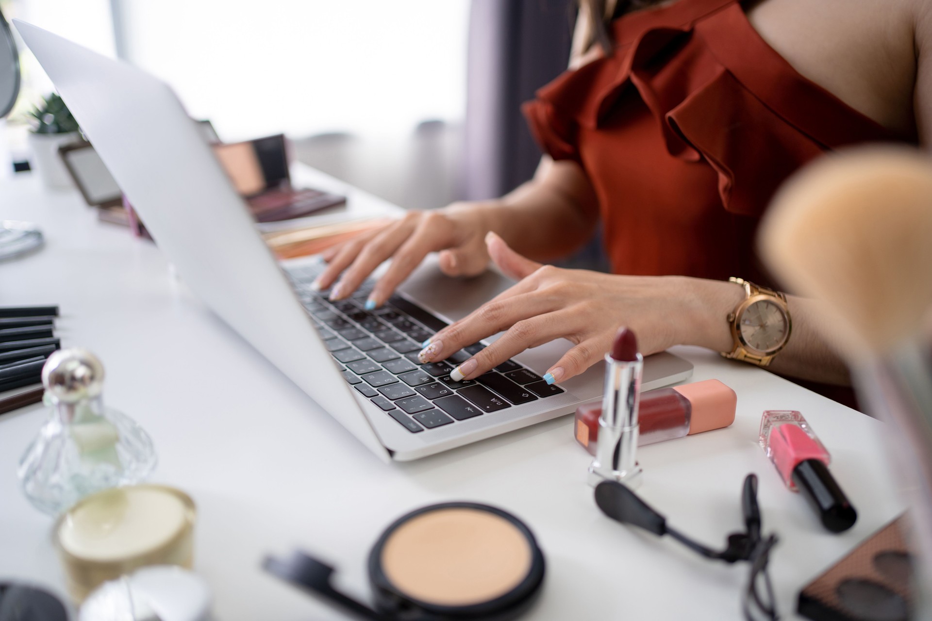 Beautiful young Asian blogger uses a computer on the table. She is shopping for cosmetics online.